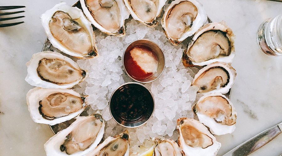 Neptune Oyster signature dishes Neptune Lobster Roll (hot with butter), Johnnycake with Smoked Trout, Oysters, Neptune Burger